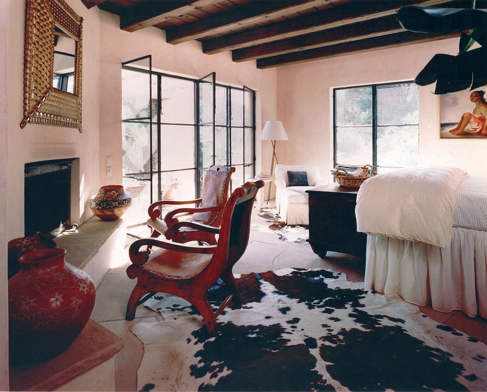 サンタバーバラにある広いサンタフェスタイルのおしゃれな主寝室 (ベージュの壁、スレートの床、コーナー設置型暖炉、石材の暖炉まわり)