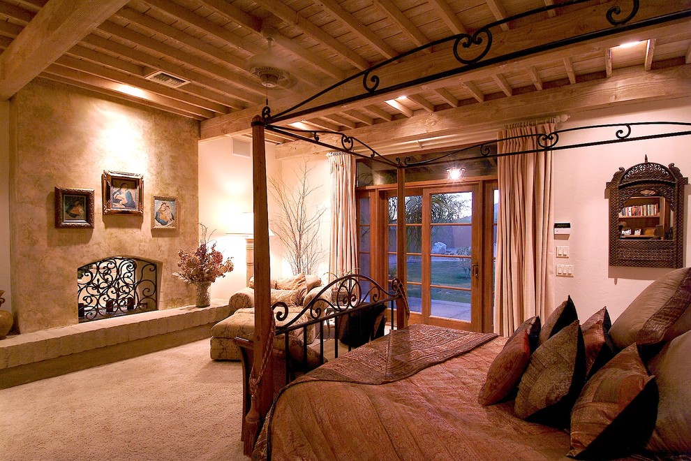 フェニックスにある中くらいな地中海スタイルのおしゃれな主寝室 (ベージュの壁、カーペット敷き、両方向型暖炉、漆喰の暖炉まわり)