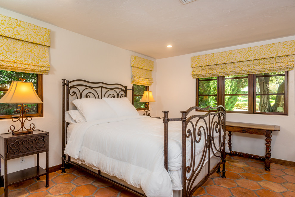 Ejemplo de habitación de invitados mediterránea con paredes blancas y suelo de baldosas de terracota