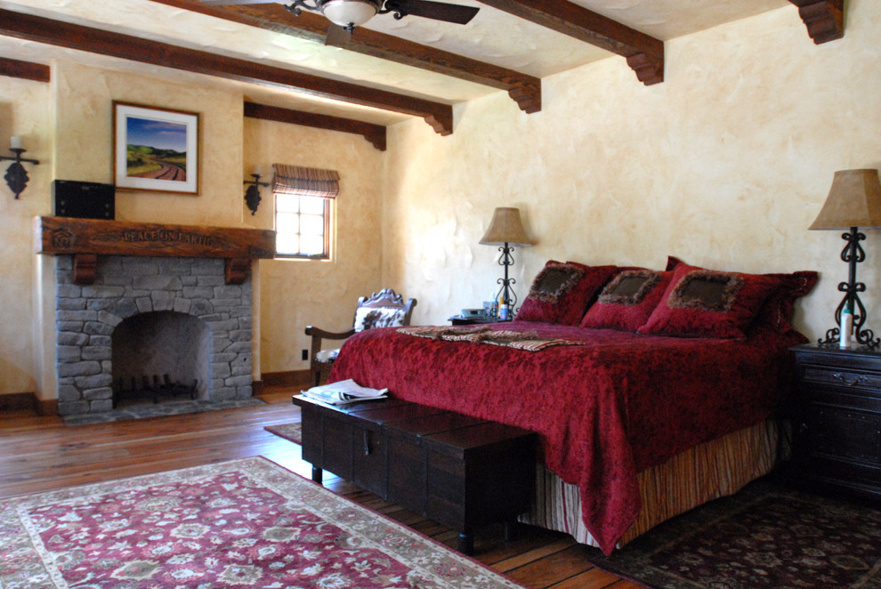 На фото: спальня среднего размера в средиземноморском стиле с стандартным камином и фасадом камина из камня