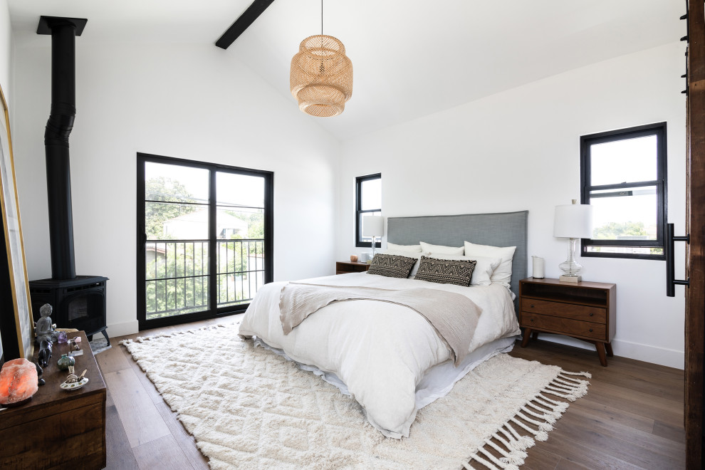 ロサンゼルスにある中くらいな地中海スタイルのおしゃれな主寝室 (白い壁、無垢フローリング、コーナー設置型暖炉、茶色い床、三角天井) のインテリア