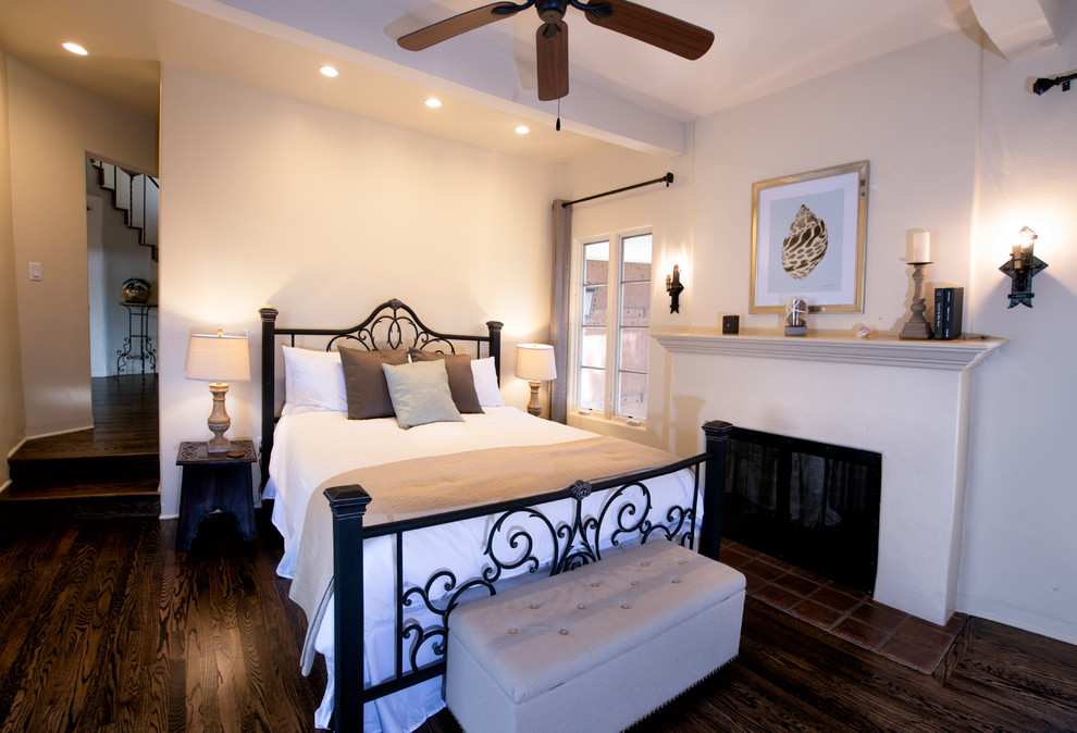 This is an example of a large mediterranean master bedroom in San Diego with white walls, dark hardwood flooring and a standard fireplace.
