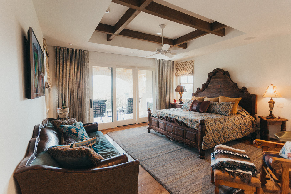 Example of a small southwest master medium tone wood floor and brown floor bedroom design in Austin with beige walls and no fireplace