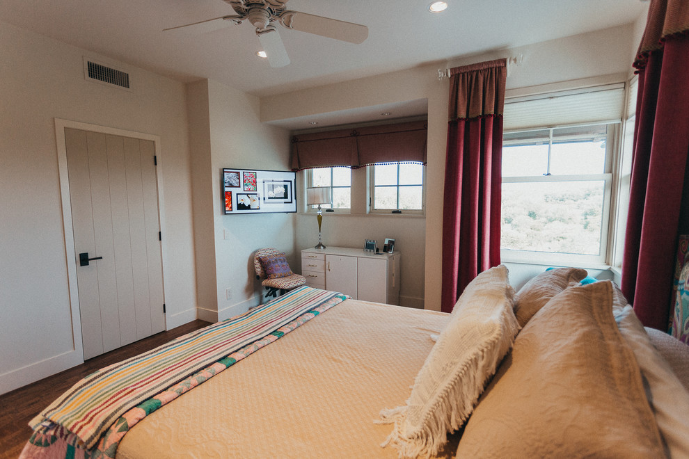Modelo de habitación de invitados de estilo americano pequeña sin chimenea con paredes beige, suelo de madera en tonos medios y suelo marrón
