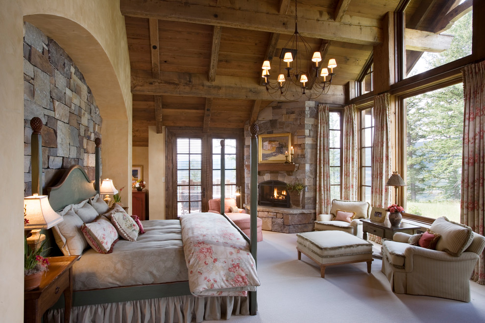 Пример оригинального дизайна: хозяйская спальня на мансарде в стиле рустика с фасадом камина из камня, ковровым покрытием и угловым камином