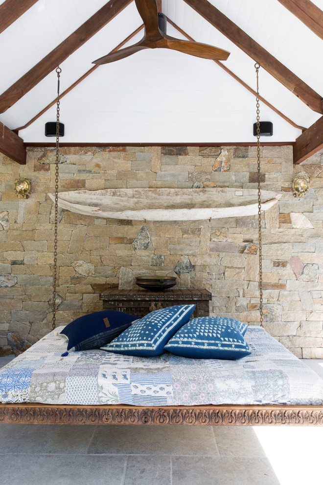Immagine di una camera da letto tropicale con pareti beige e pavimento grigio