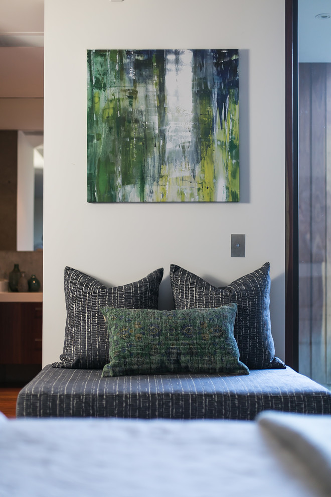 Ejemplo de habitación de invitados actual con paredes blancas y suelo de madera en tonos medios