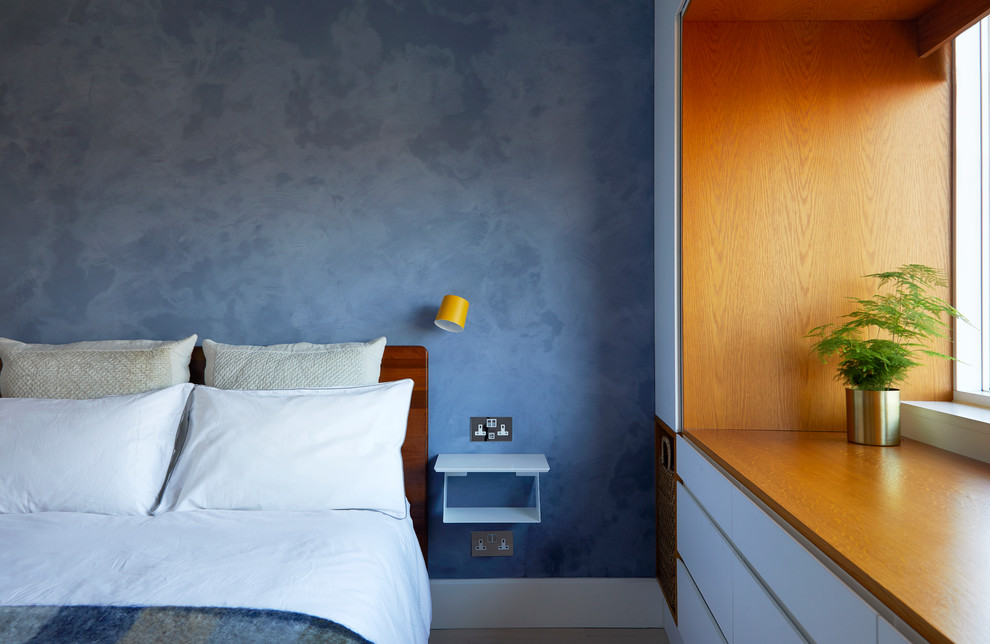 Kleines Modernes Hauptschlafzimmer ohne Kamin mit blauer Wandfarbe, hellem Holzboden und grauem Boden in London