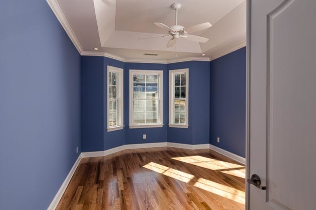 Immagine di una grande camera matrimoniale american style con pareti blu e pavimento in legno massello medio