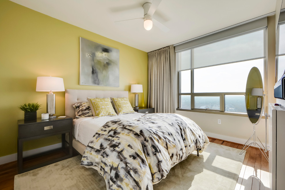 This is an example of a small traditional master bedroom in Austin with yellow walls and light hardwood flooring.
