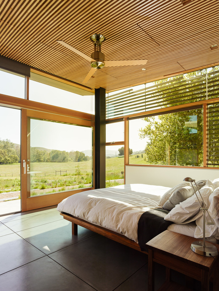 Aménagement d'une chambre contemporaine avec un mur blanc et sol en béton ciré.