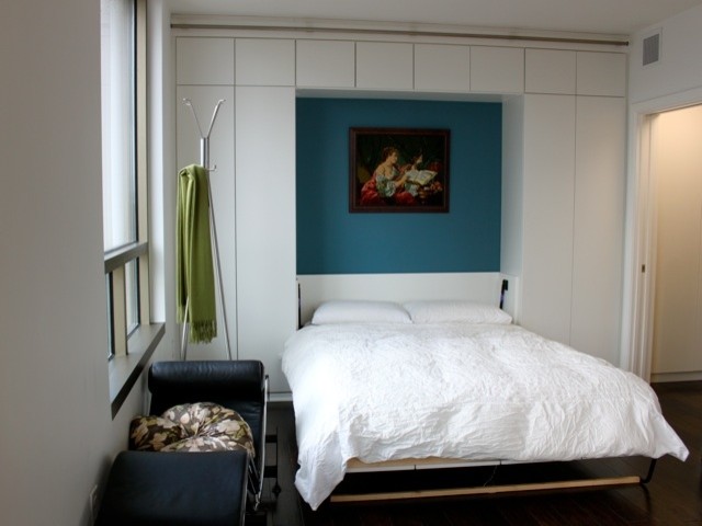 Imagen de dormitorio moderno de tamaño medio sin chimenea con paredes blancas y suelo de madera oscura
