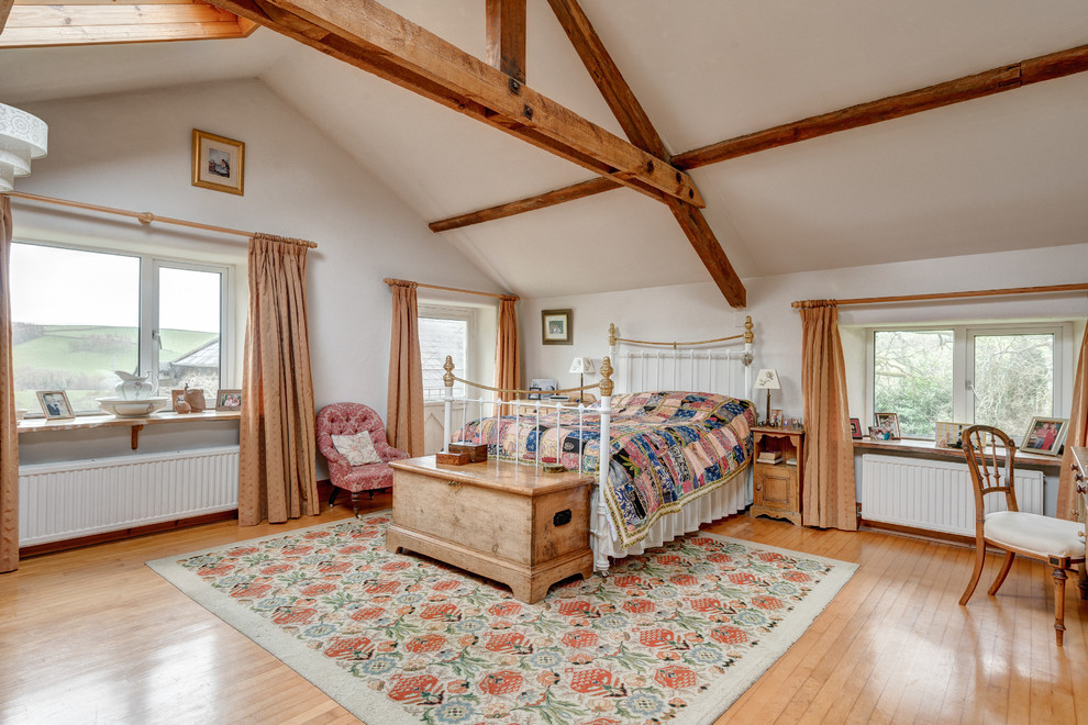 Großes Country Hauptschlafzimmer mit hellem Holzboden und beiger Wandfarbe in Devon