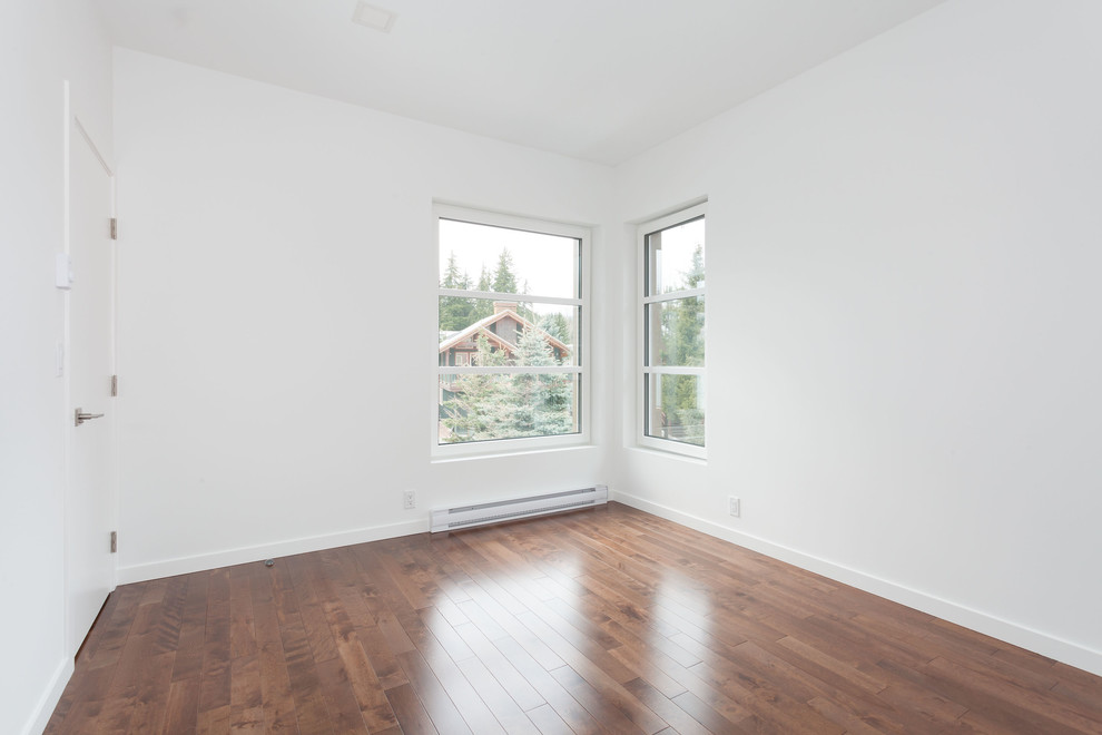 Esempio di una camera matrimoniale minimalista di medie dimensioni con pareti bianche, pavimento marrone, pavimento in legno massello medio e nessun camino