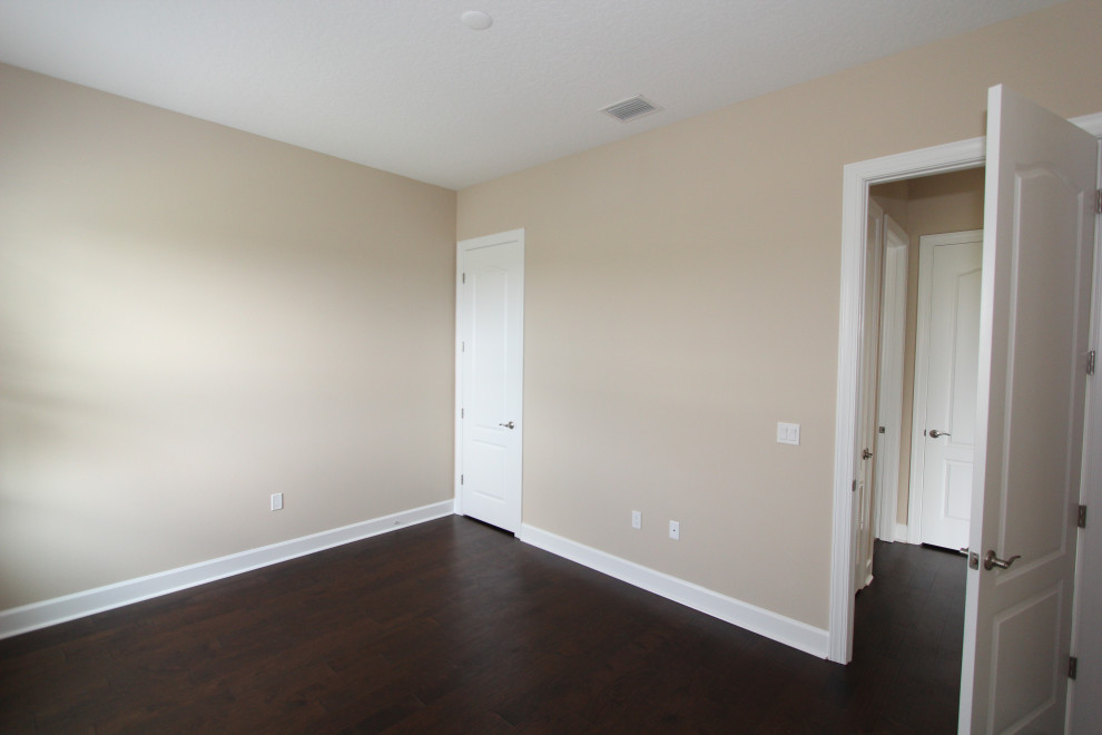 Cette image montre une grande chambre d'amis traditionnelle avec un mur beige, parquet foncé et un sol marron.