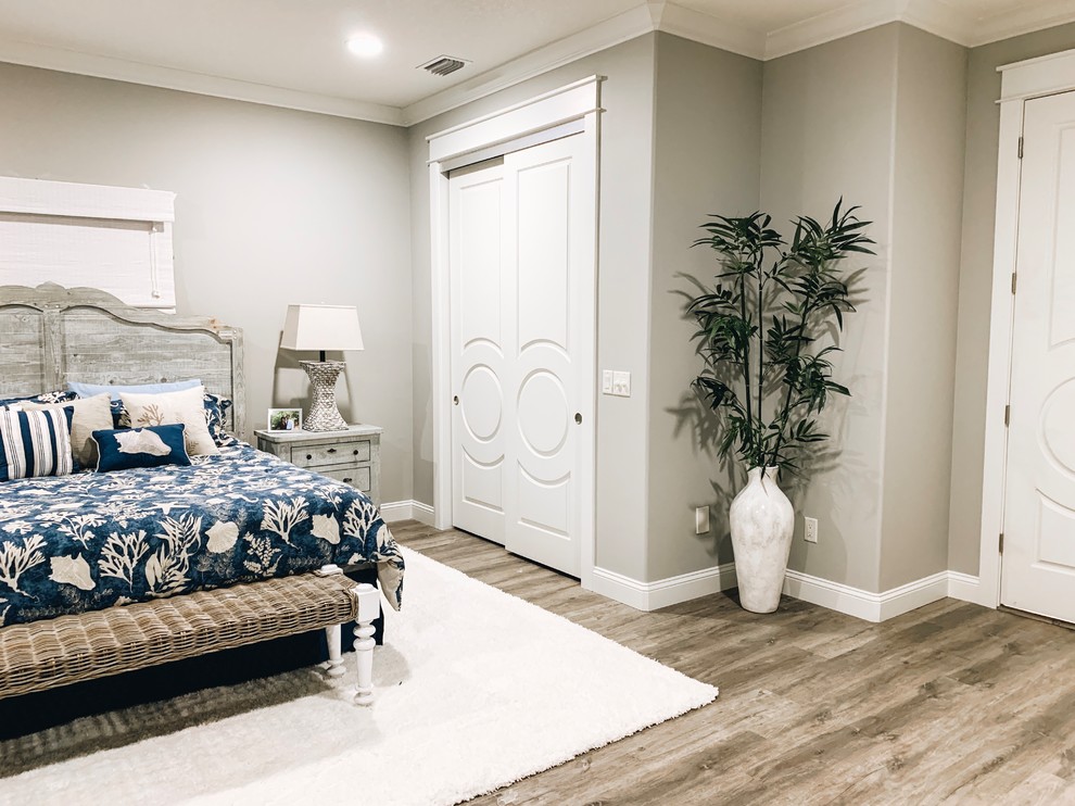 Imagen de dormitorio principal costero grande con paredes grises, suelo laminado y suelo gris