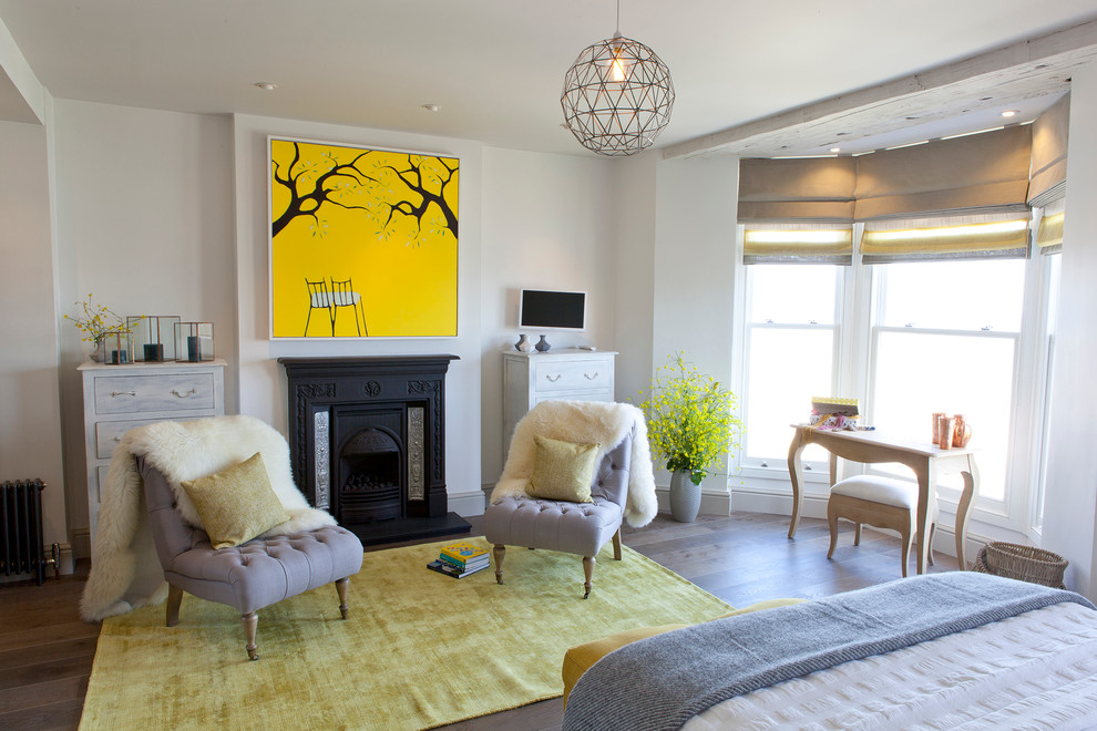 Maritimes Hauptschlafzimmer mit weißer Wandfarbe, braunem Holzboden und Kamin in Cornwall