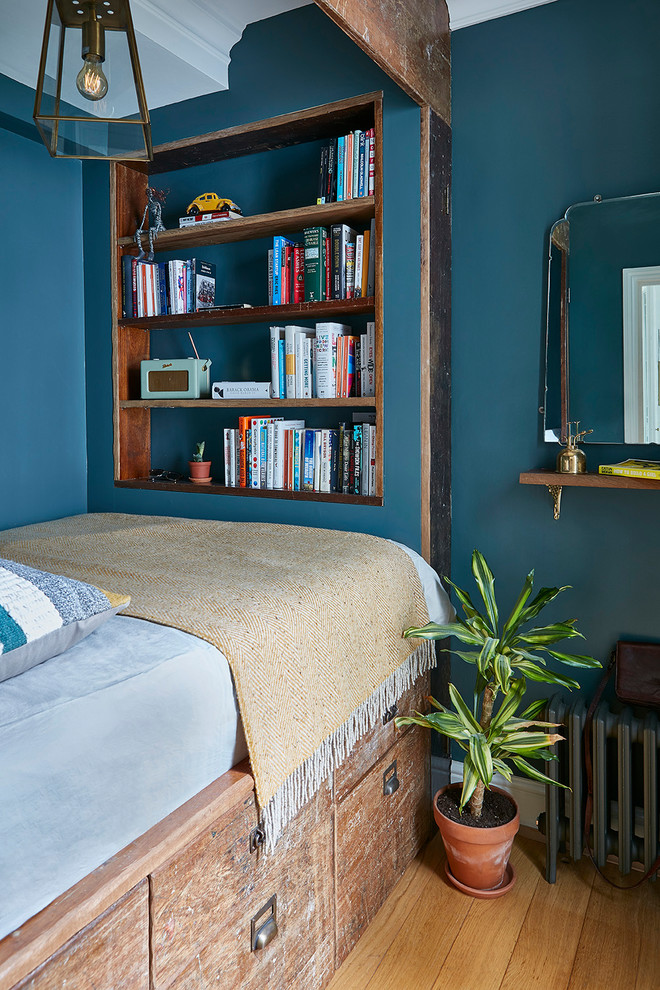 Design ideas for a small traditional guest bedroom in London with blue walls, medium hardwood flooring and brown floors.