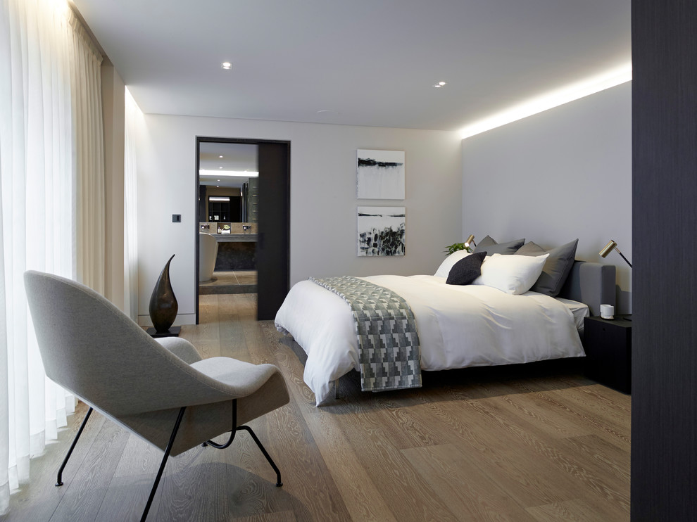 Large trendy master light wood floor bedroom photo in London with gray walls