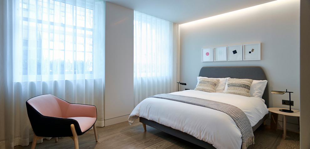 Diseño de habitación de invitados actual de tamaño medio con paredes grises y suelo de madera clara