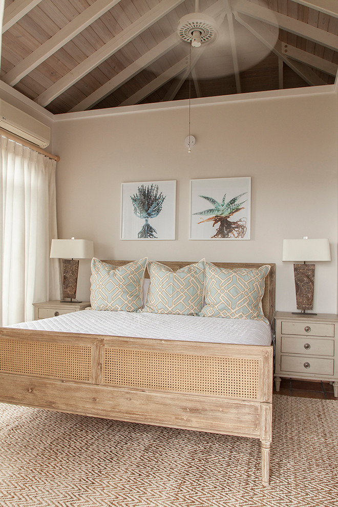 Modelo de dormitorio principal y abovedado exótico sin chimenea con paredes beige, suelo de madera en tonos medios y suelo marrón