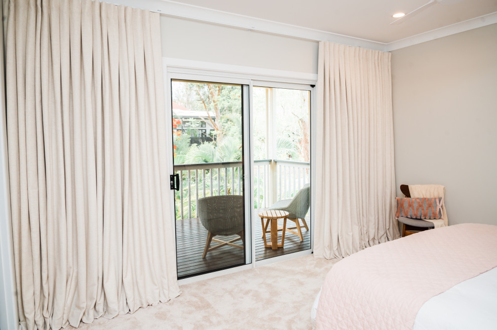 Modelo de dormitorio principal de tamaño medio con paredes beige, moqueta y suelo beige