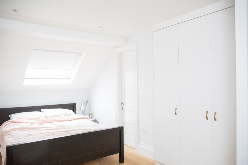 Cette image montre une petite chambre d'amis minimaliste avec un mur blanc, parquet clair et un sol marron.