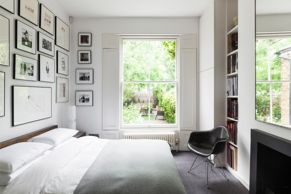 Example of a trendy guest carpeted bedroom design in London with white walls and a standard fireplace