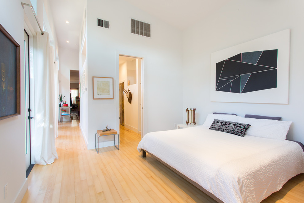 Foto de dormitorio principal actual con paredes blancas, suelo de madera clara y suelo beige