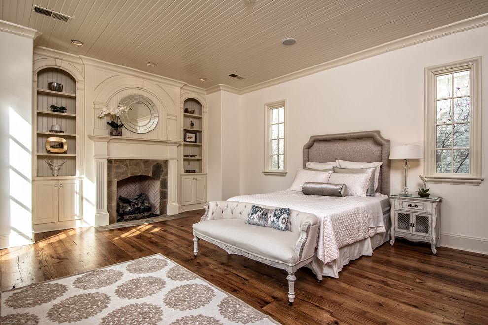 Foto de dormitorio de estilo de casa de campo grande con paredes blancas, suelo de madera oscura, todas las chimeneas y marco de chimenea de piedra