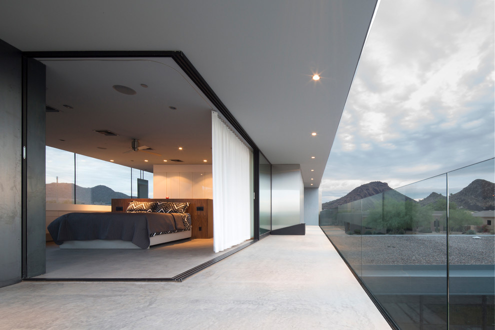На фото: хозяйская спальня среднего размера в стиле модернизм с белыми стенами и бетонным полом без камина