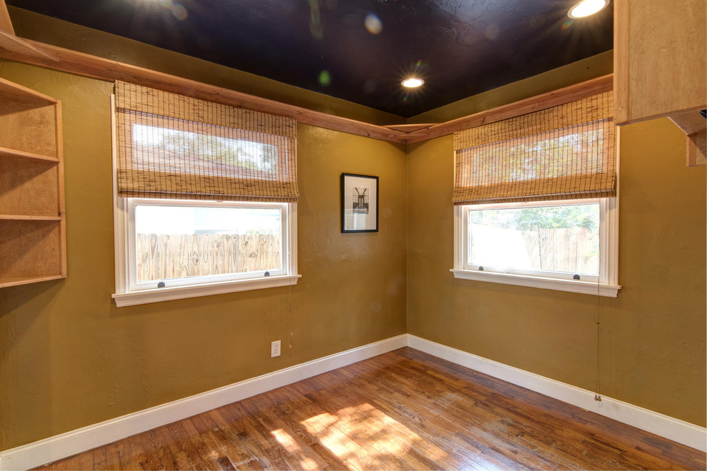 Idée de décoration pour une chambre d'amis tradition de taille moyenne avec un mur jaune et un sol en bois brun.