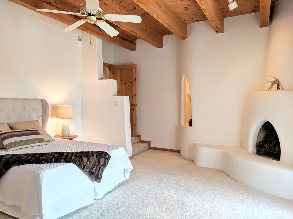 Идея дизайна: хозяйская спальня среднего размера в стиле фьюжн с ковровым покрытием, угловым камином, фасадом камина из штукатурки, бежевыми стенами и бежевым полом