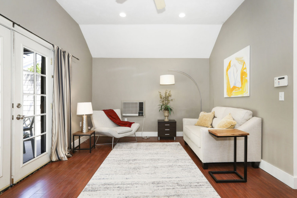 This is an example of a small modern guest bedroom in Los Angeles with grey walls, laminate floors, brown floors and a vaulted ceiling.