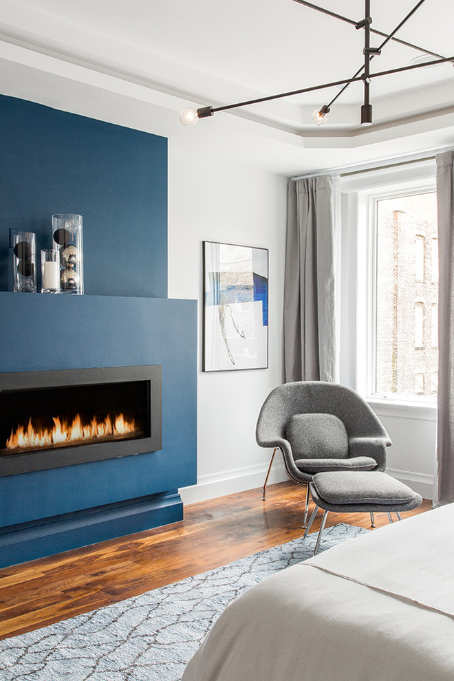 Mittelgroßes Modernes Hauptschlafzimmer mit blauer Wandfarbe, dunklem Holzboden, Kamin und Kaminumrandung aus Metall in New York