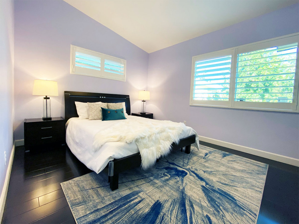 Réalisation d'une petite chambre d'amis minimaliste avec un mur bleu, sol en stratifié, un sol noir et un plafond voûté.