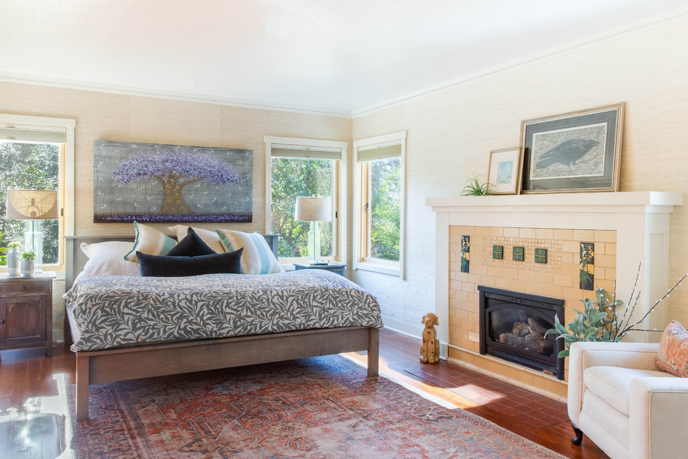 Exempel på ett klassiskt sovrum, med beige väggar, mörkt trägolv, en standard öppen spis, en spiselkrans i trä och brunt golv