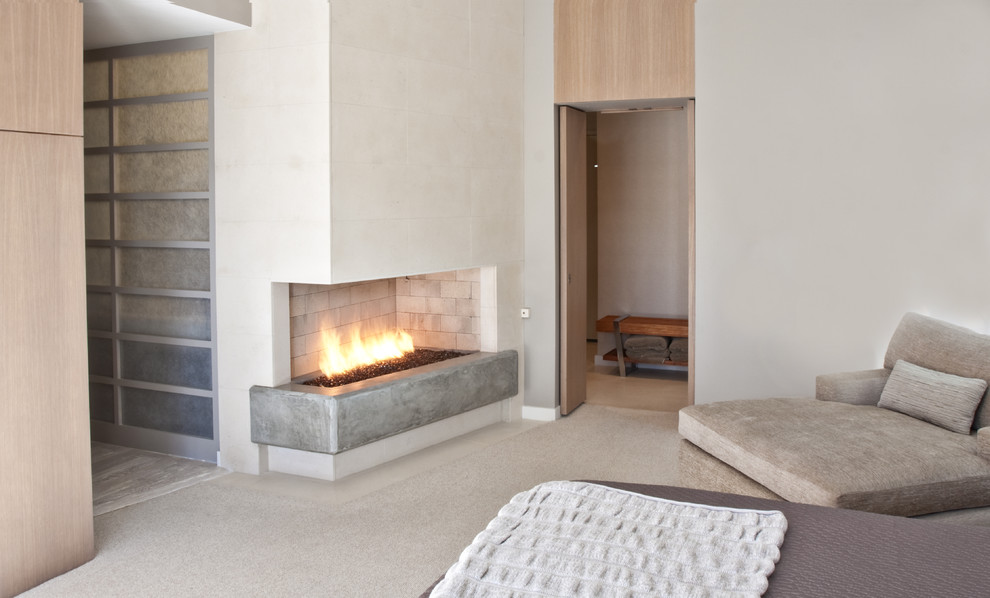 Modernes Schlafzimmer mit Kaminumrandung aus Beton und Eckkamin in Dallas