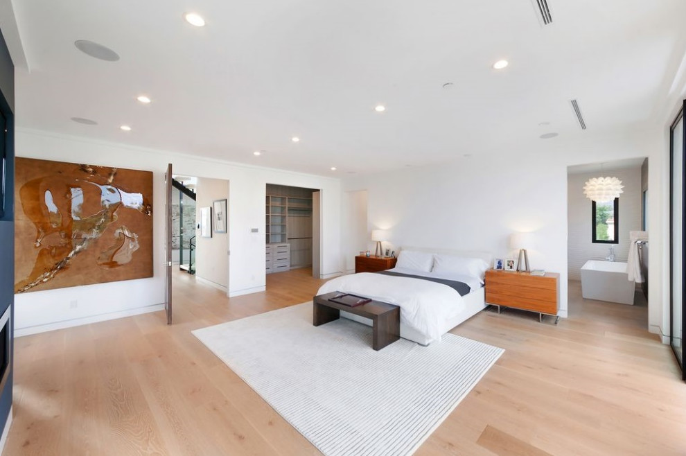 Example of a large trendy master light wood floor and beige floor bedroom design in Los Angeles with white walls
