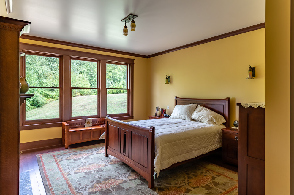 シアトルにあるヴィクトリアン調のおしゃれな主寝室 (茶色い床、黄色い壁、無垢フローリング)