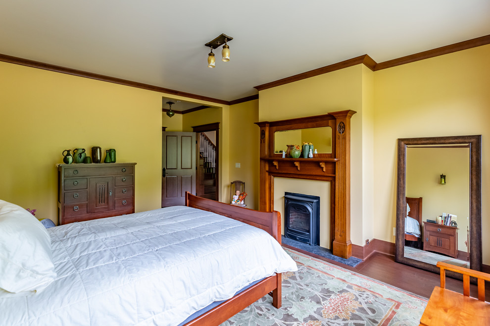 Foto de dormitorio principal clásico con suelo de madera oscura, todas las chimeneas, marco de chimenea de madera y suelo marrón