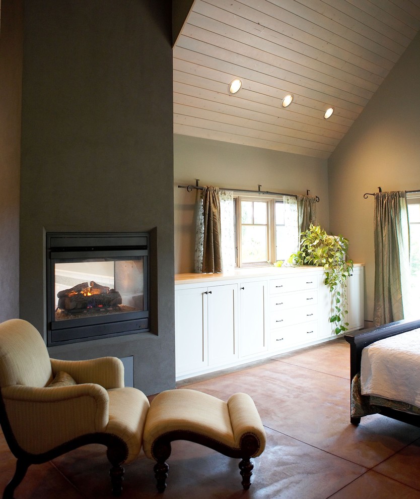 Imagen de dormitorio ecléctico con marco de chimenea de hormigón y chimenea de doble cara