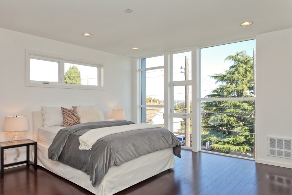 Modern grey and pink bedroom in Seattle with white walls and dark hardwood flooring.