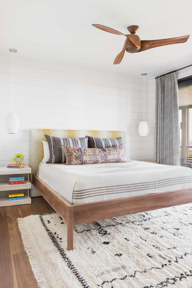 Diseño de dormitorio costero con paredes blancas, suelo de madera en tonos medios y suelo marrón