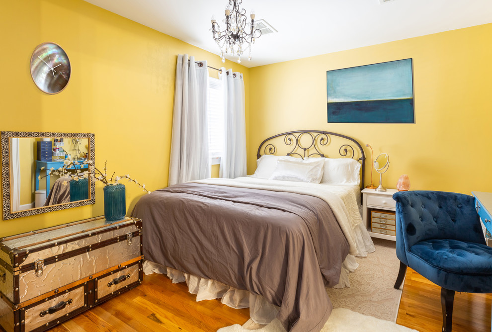 Diseño de dormitorio principal clásico de tamaño medio sin chimenea con paredes amarillas, suelo de madera clara y suelo marrón
