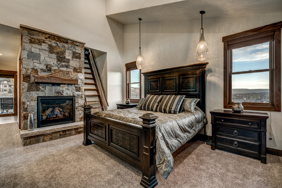 Rustikales Hauptschlafzimmer mit beiger Wandfarbe, Teppichboden, Kamin und Kaminumrandung aus Stein in Denver