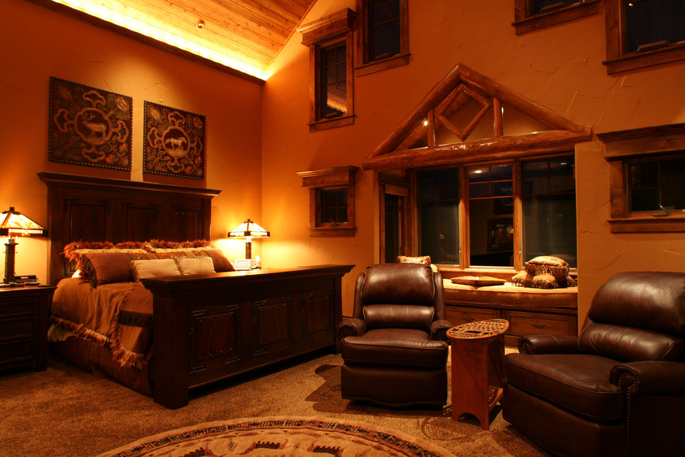 На фото: огромная хозяйская спальня в стиле рустика с бежевыми стенами, двусторонним камином и фасадом камина из камня