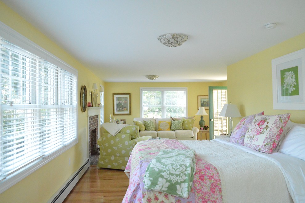 На фото: хозяйская спальня среднего размера в морском стиле с желтыми стенами, паркетным полом среднего тона, стандартным камином и фасадом камина из кирпича