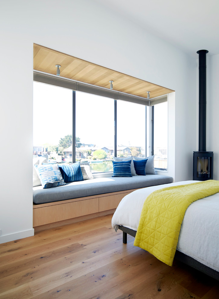 Modernes Schlafzimmer mit weißer Wandfarbe, braunem Holzboden und Kaminofen in San Francisco