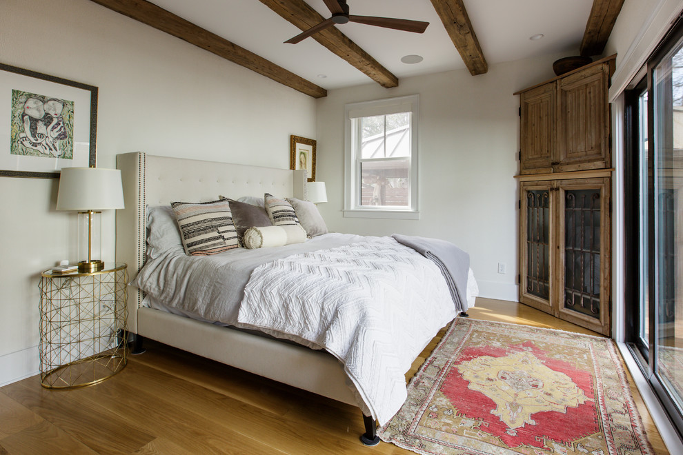 Modelo de dormitorio bohemio con paredes blancas, suelo de madera en tonos medios y suelo marrón